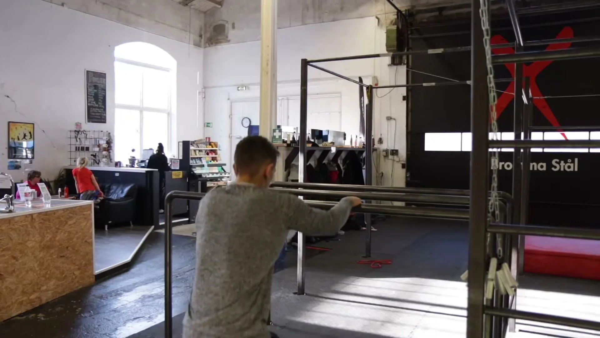 Full B-boy leg trick in progress on parallel bars, leg driving forward to complete the movement