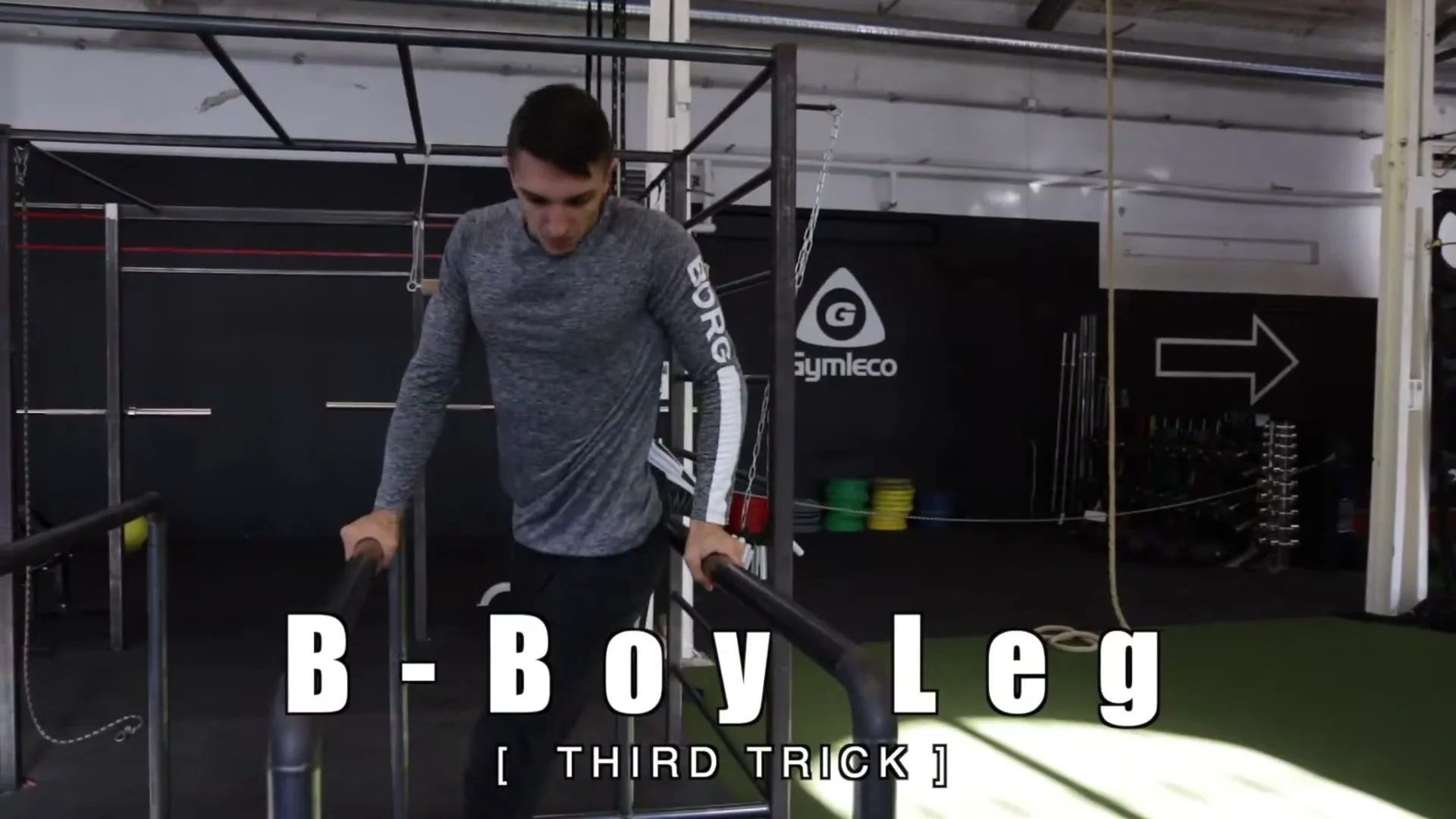 B-boy leg trick on parallel bars showing the starting position between the bars with straight arms