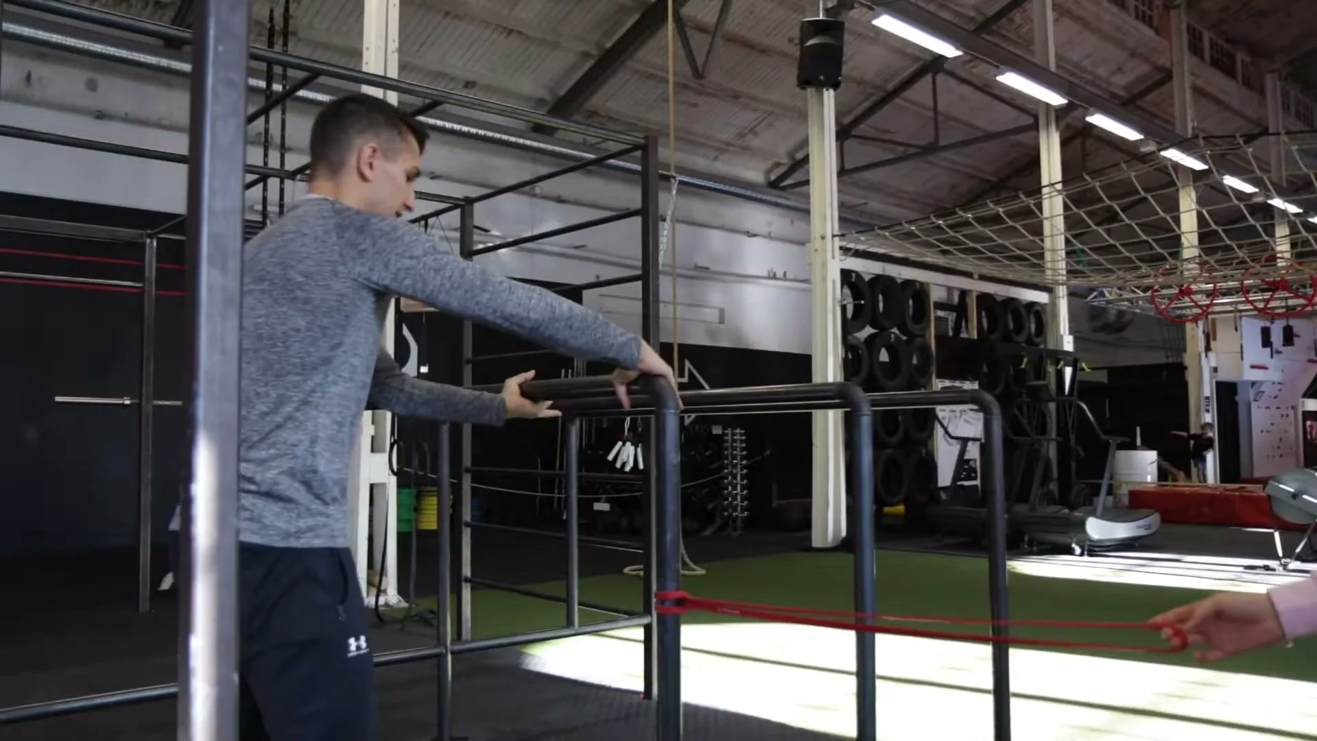Resistance band drill for the jump in trick, band stretched low across the parallel bars as a height guide