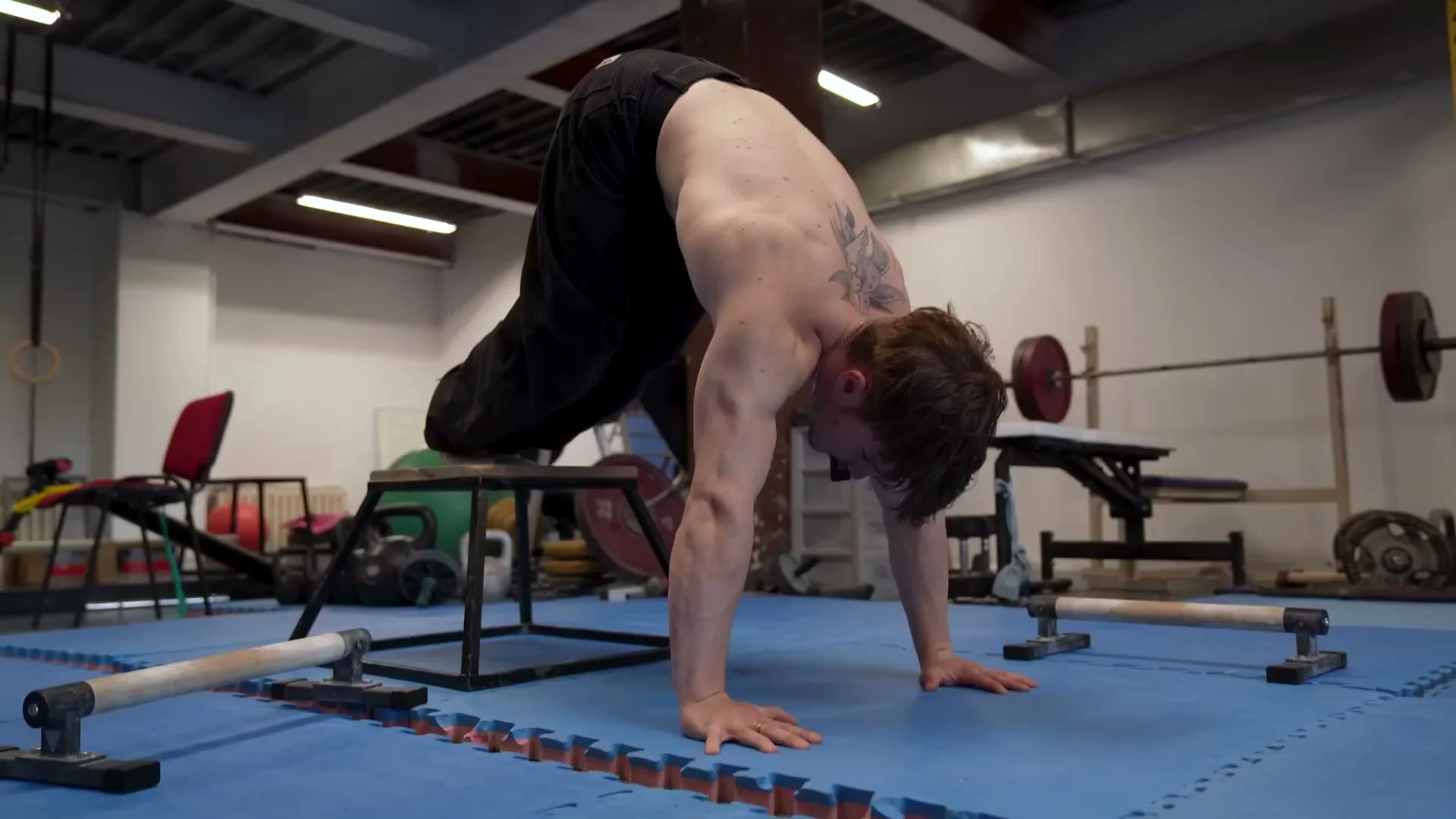 Nathan demonstrating pike push-up with feet elevated and torso vertical, pushing forward