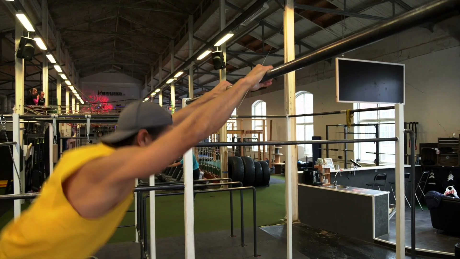 Daniel Flefil performing the V-sit muscle up on the bar: legs extended and over the bar mid-transition, pulling into the L-sit position at the top