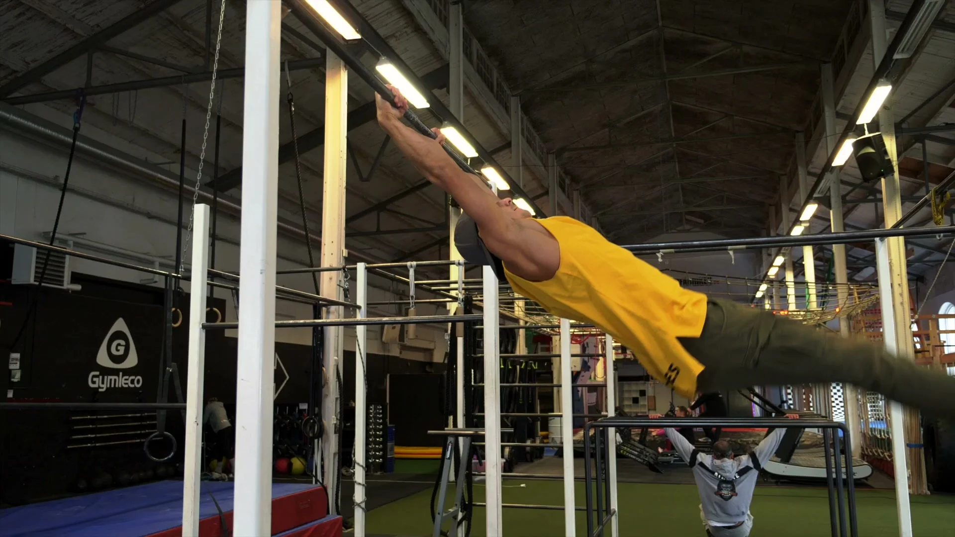 Straight-leg drive for the V-sit muscle up: legs brought to chest and driving over the bar in the swing phase, arms straight throughout